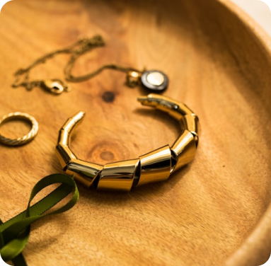 Gold bracelet and jewelry on a wooden tray